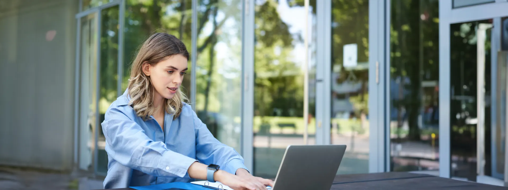 Designer working on a laptop beside a glass office window